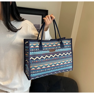 Detail of vintage geometric canvas tote featuring a brown leather patch and woven pattern