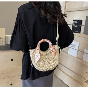 Detail of hand-woven straw crossbody bag with floral scarf accent and drawstring closure