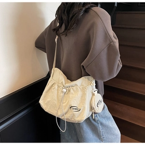 Detail of off-white nylon drawstring crossbody bag with matching round coin pouch