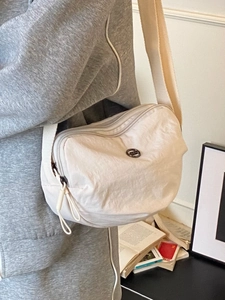 Minimalist beige nylon half-moon crossbody bag with adjustable strap shown in daily use
