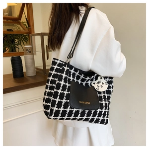 Dettaglio della borsa tote in tweed a scacchi con tasca in pelle e ciondolo tigre