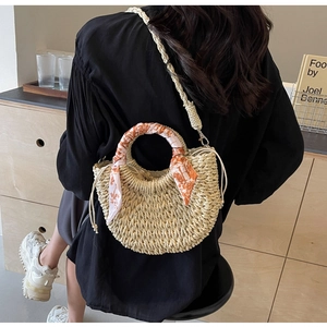 Detail of woven straw crossbody bag featuring decorative printed silk scarf and drawstring closure