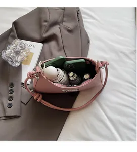 Spacious interior of pink leather shoulder bag holding a phone, umbrella and makeup