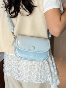 Glossy light blue crossbody bag with round buckle on white lace dress outfit