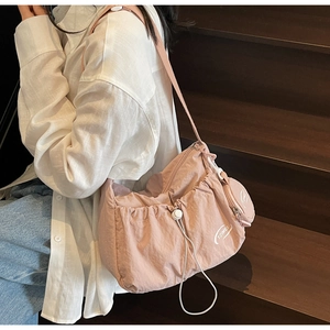 Pink nylon pleated shoulder bag with drawstring detail and round coin purse on stairs