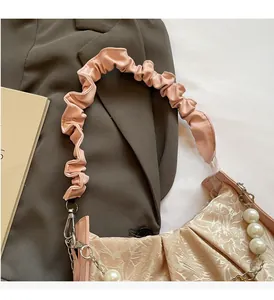 Detail of ruched handle and pearl chain charm on the chic pleated crossbody cloud bag