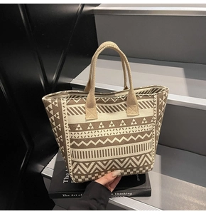 Detail of geometric jacquard tote bag with ethnic patterns and woven handles on a step