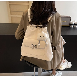 Detail of beige backpack with silver butterfly buckle and white cloud plush pendant