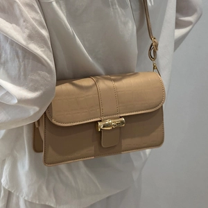 Elegant beige croc-embossed shoulder bag with a gold bamboo twist lock on model