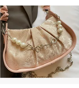 Detail of the elegant jacquard floral fabric and decorative large pearl chain on bag
