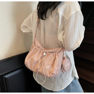 Detail of light pink nylon drawstring crossbody bag with round coin purse on a model