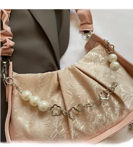 Detail of floral jacquard satin handbag with pearl chain and elegant pleated clouds design