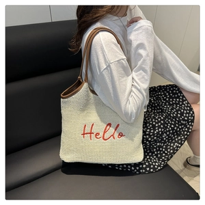 Detail of white woven tote bag featuring red Hello embroidery and brown leather handles