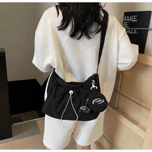 Detail of black nylon crossbody bag featuring a drawstring design and round coin purse