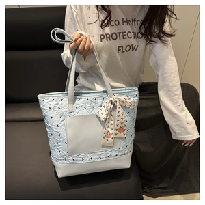 Quilted light blue tote bag with patterned silk scarf handle detail on leather sofa
