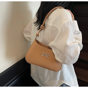 Detail of camel shoulder bag with silver bow hardware and chic knotted strap design
