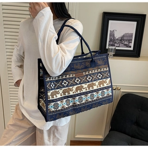 Close-up of bohemian canvas tote bag featuring elephant patterns and fashion label detail
