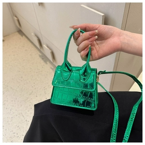 Close-up of mini green metallic handbag with crocodile texture and thin shoulder strap