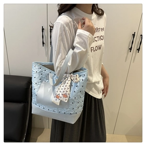 Close-up of light blue quilted leather tote bag with decorative silk scarf on handle
