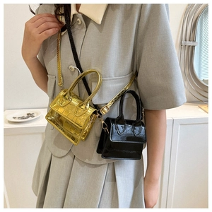 Detailed macro view of the mini handbag's croc-effect texture and golden metallic finish