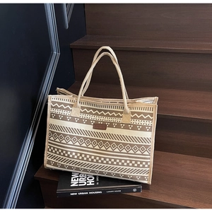 Detailed close-up of geometric woven pattern and leather brand label on canvas tote bag