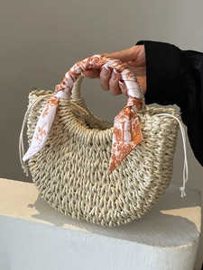 Chic beige woven straw crescent handbag with decorative printed silk scarf on the handle