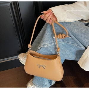 Detail of camel leather underarm bag with silver bow buckle and knotted shoulder strap
