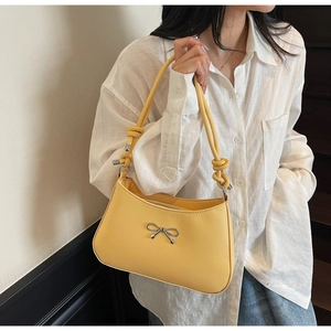 Detail of light yellow leather shoulder bag with silver bow and knotted handle