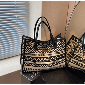 Detail of vintage canvas tote with geometric patterns and brown leather logo tag