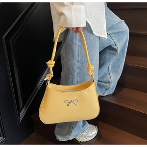 Detail of yellow PU leather shoulder bag with silver metal bow and knotted strap design