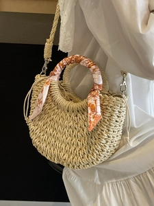 Handwoven straw crossbody bag with round handles and orange printed scarf decoration
