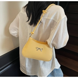 Detailed back view of model wearing a bright yellow PU leather shoulder bag with silver bow