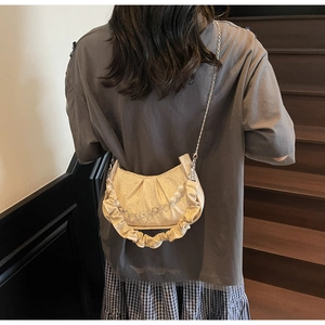 Detailed close-up of cream pleated cloud bag with elegant pearl and floral chain