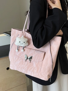 Pink pleated tote bag with silver butterfly buckle and white plush charm on a model
