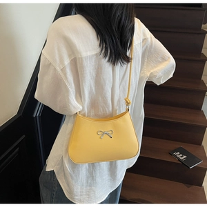 Detail of yellow leather Hobo bag with silver metal bow and knotted shoulder strap