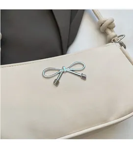 Detail of silver bow metal clasp and strap knot on off-white minimalist leather bag