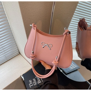 Detail of pink shoulder bag featuring silver bow buckle and knotted handle texture