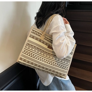 Ethnic pattern canvas tote bag with woven handles shown being carried by a model
