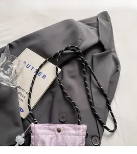Detail of light purple drawstring bucket bag with floral charm and woven strap