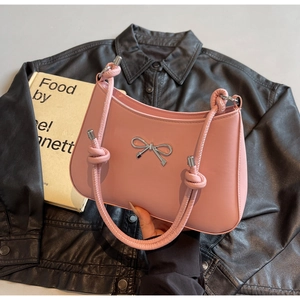 Close-up of pink leather handbag featuring silver bow and braided knotted handle
