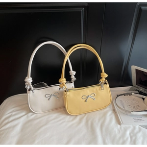 Detail of minimalist leather underarm bags with bow metal decor and knotted handles