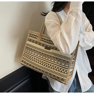 Close-up of geometric pattern canvas tote bag with a branded leather fashion label