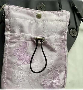 Detail of lavender butterfly embroidery on a textured drawstring bucket bag for women