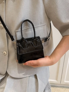 Mini black crocodile embossed handbag with gold hardware shown with gray blazer