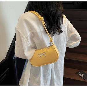 Detail of yellow baguette shoulder bag with silver bow ornament and knotted strap detail