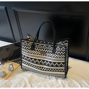 Detail of bohemian canvas tote featuring geometric patterns and brown leather logo tag
