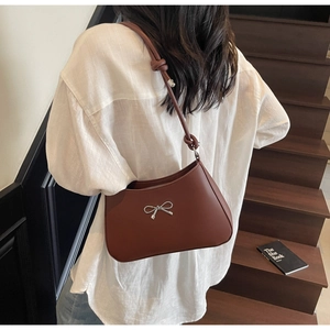 Caramel leather shoulder bag featuring a silver metal bow and knotted strap detail