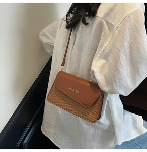 Detail of a brown leather and woven texture crossbody bag worn by a model