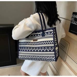 Close-up of vintage canvas tote bag with ethnic geometric patterns and blue handles