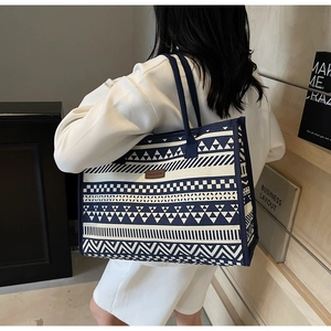 Close-up of geometric pattern canvas tote bag with fashion leather patch and blue strap